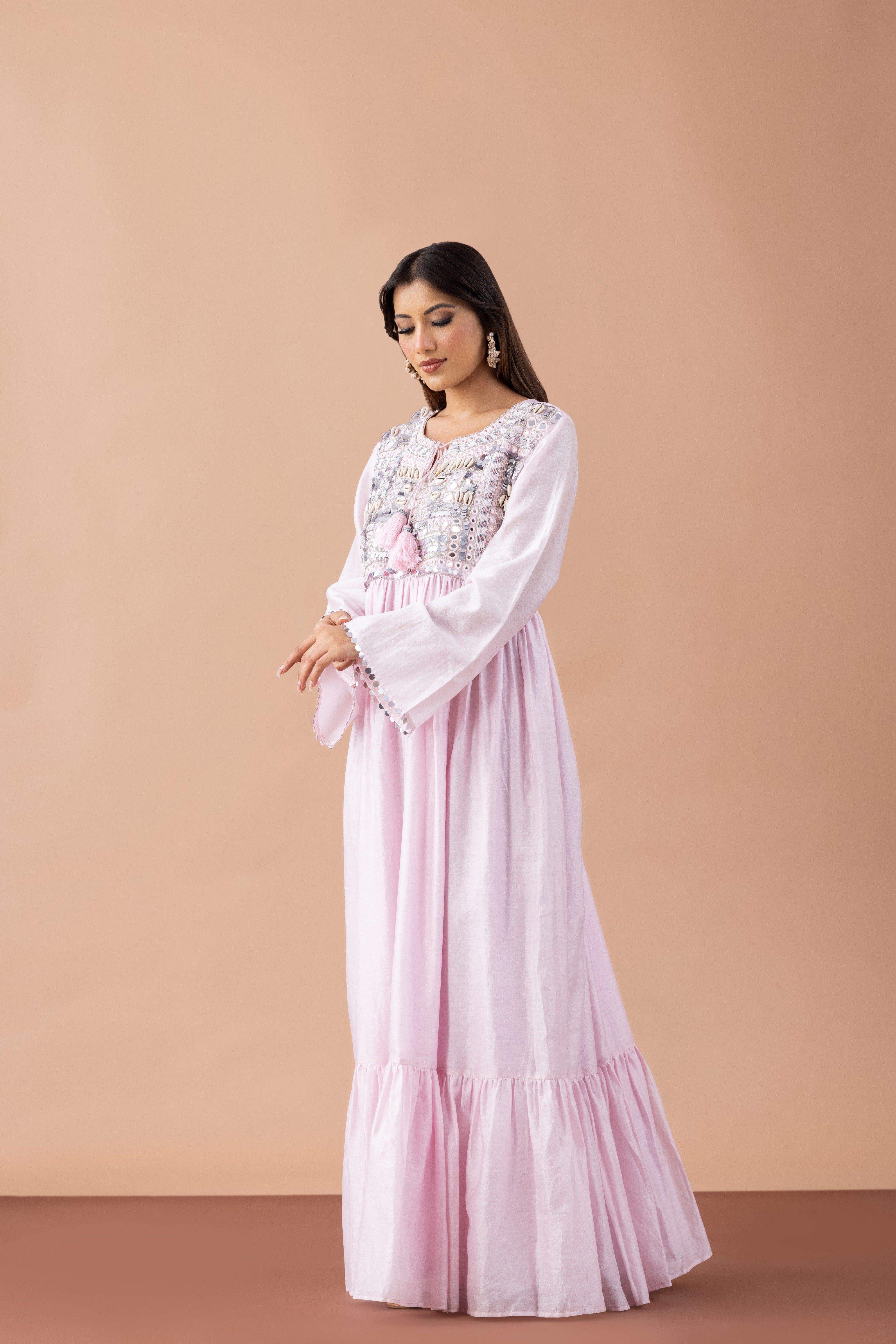 Woman wearing a pink dress with white lace details against a beige background