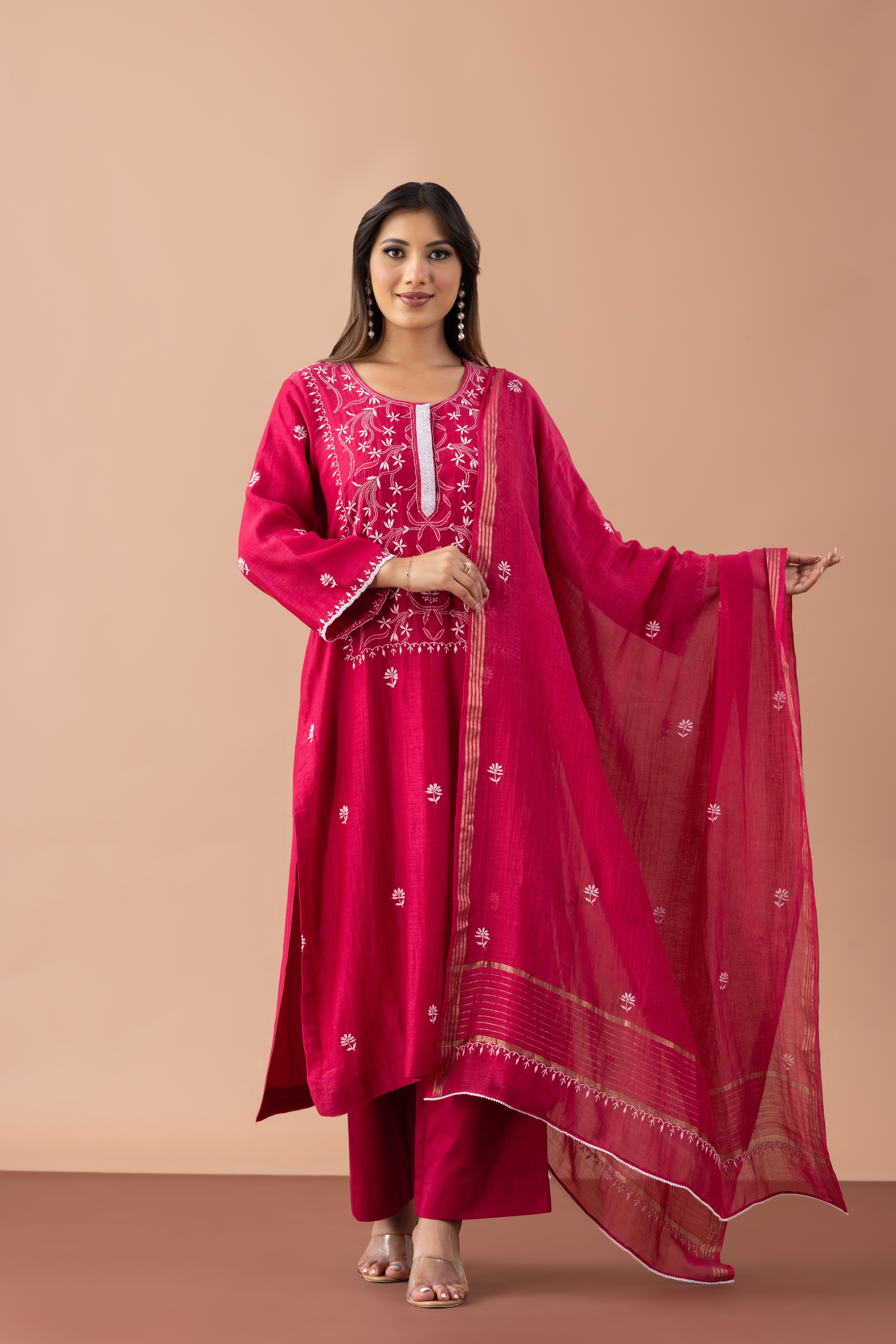 Woman wearing a pink traditional outfit with a dupatta on a beige background