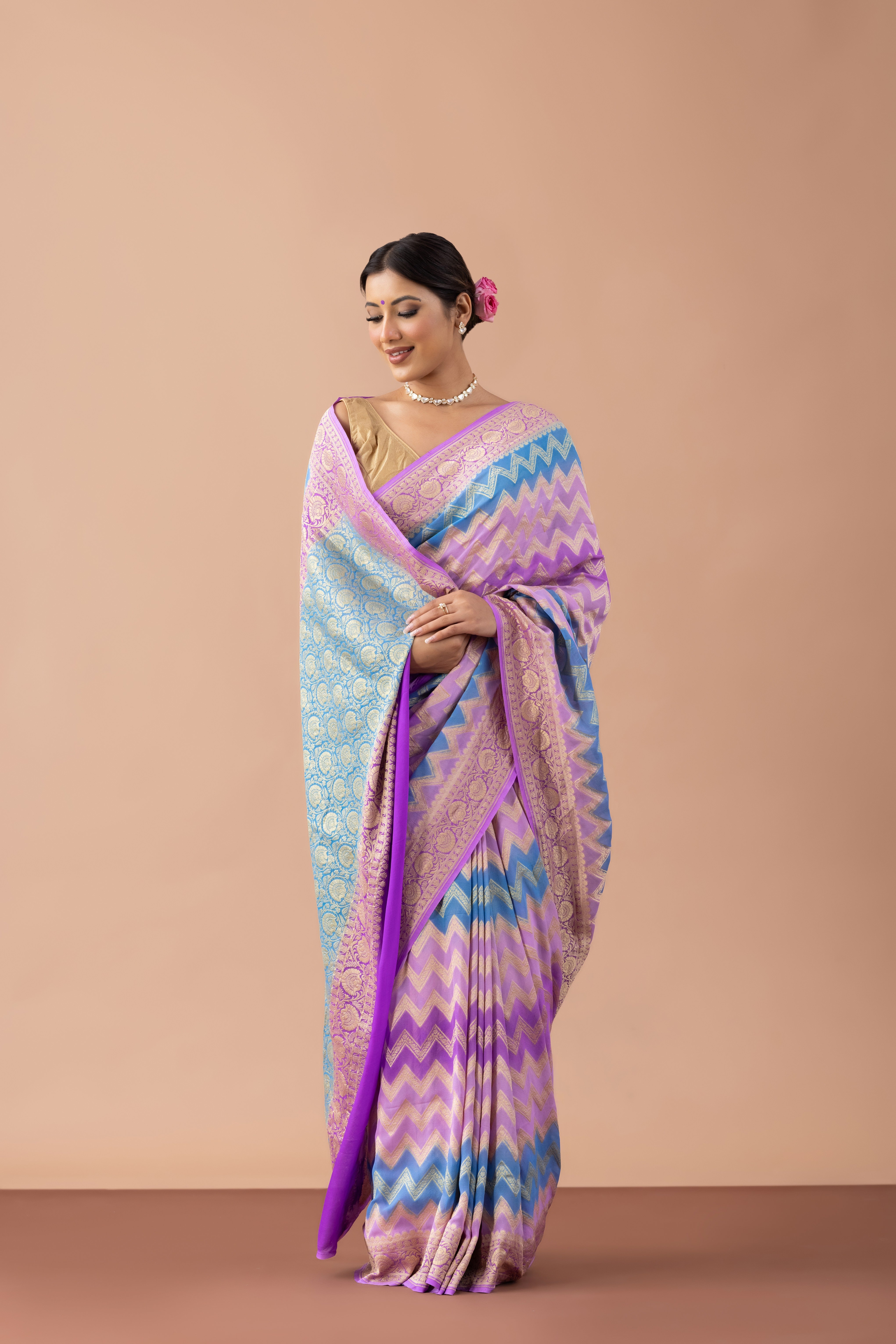Woman wearing a colorful saree with a zigzag pattern against a beige background