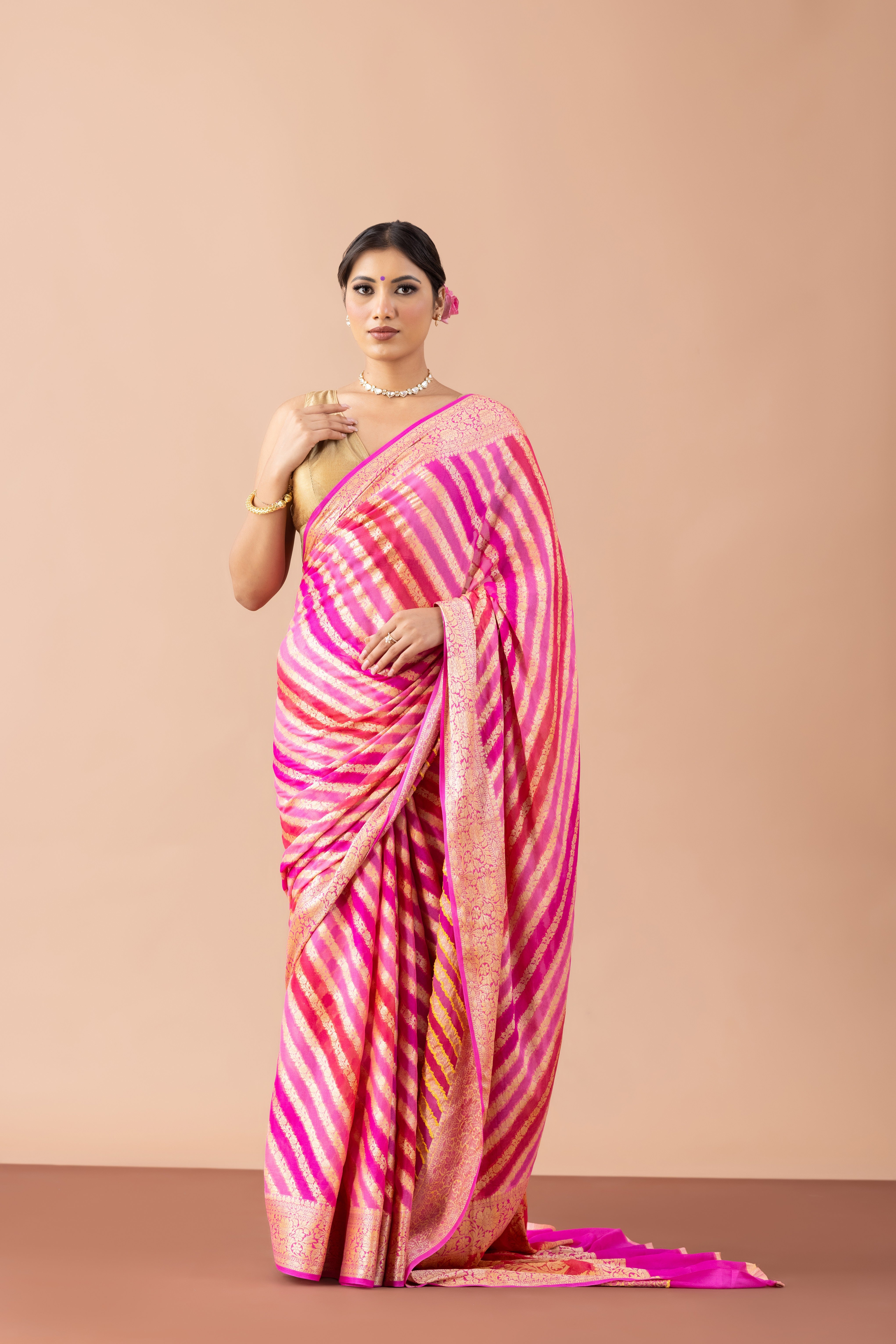 Woman wearing a pink and orange saree against a beige background